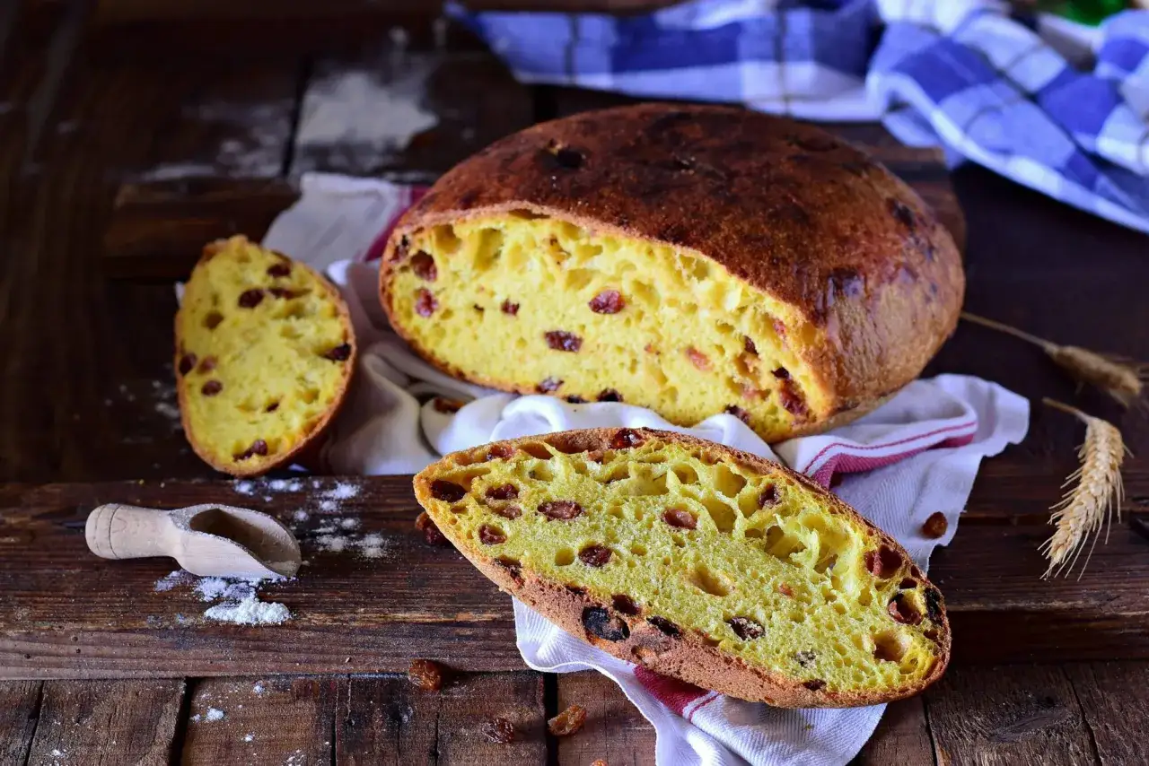 Panina aretina soffice e dorata, con uvetta succosa, su un tagliere rustico.