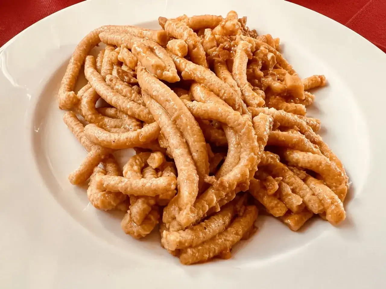 Pici all'aglione, un classico da provare ad Arezzo cosa mangiare. Pasta fatta a mano condita con un sugo saporito.