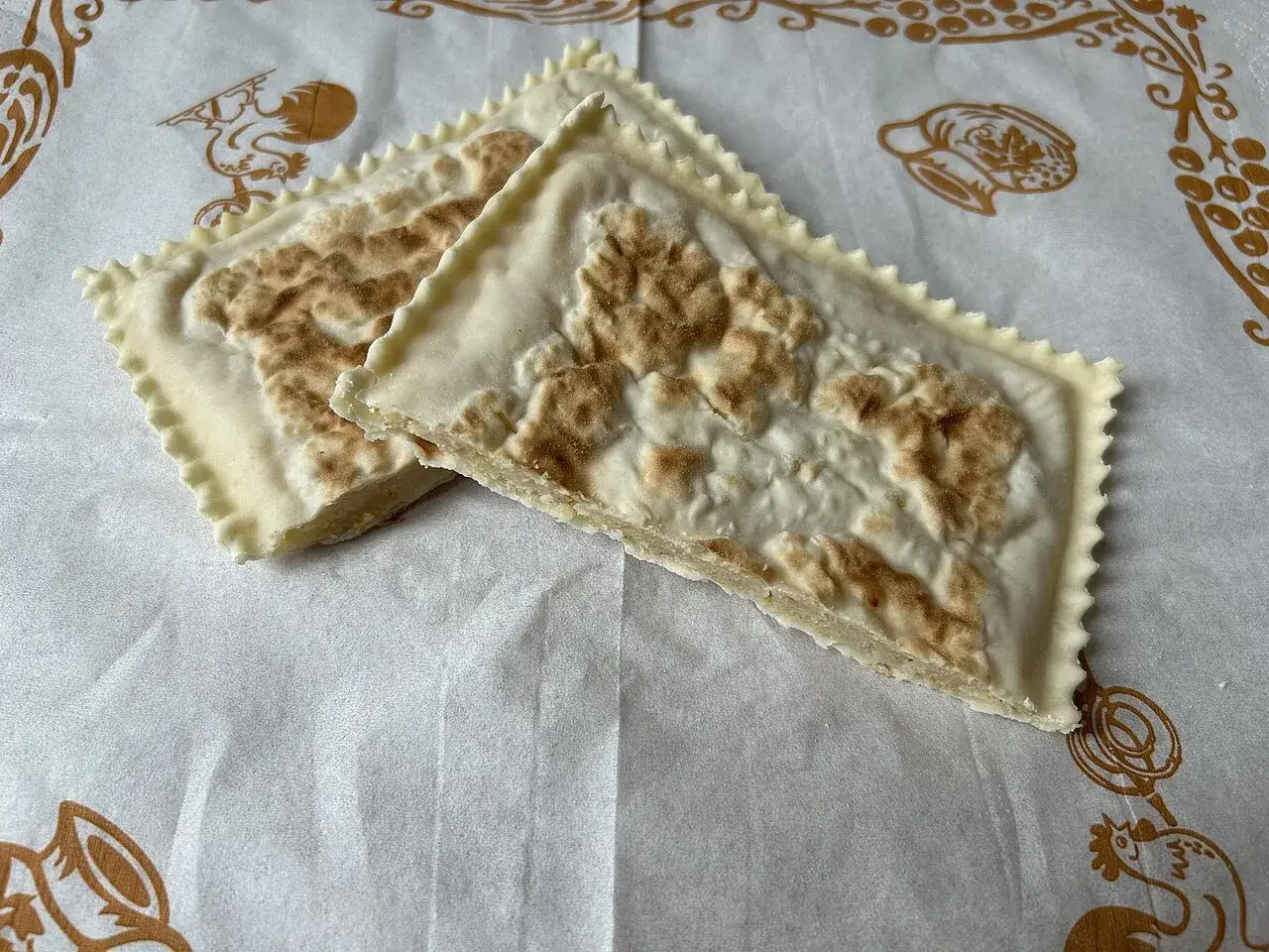 Tortelli alla lastra casentino, un sapore autentico su carta decorata con galline e uva.