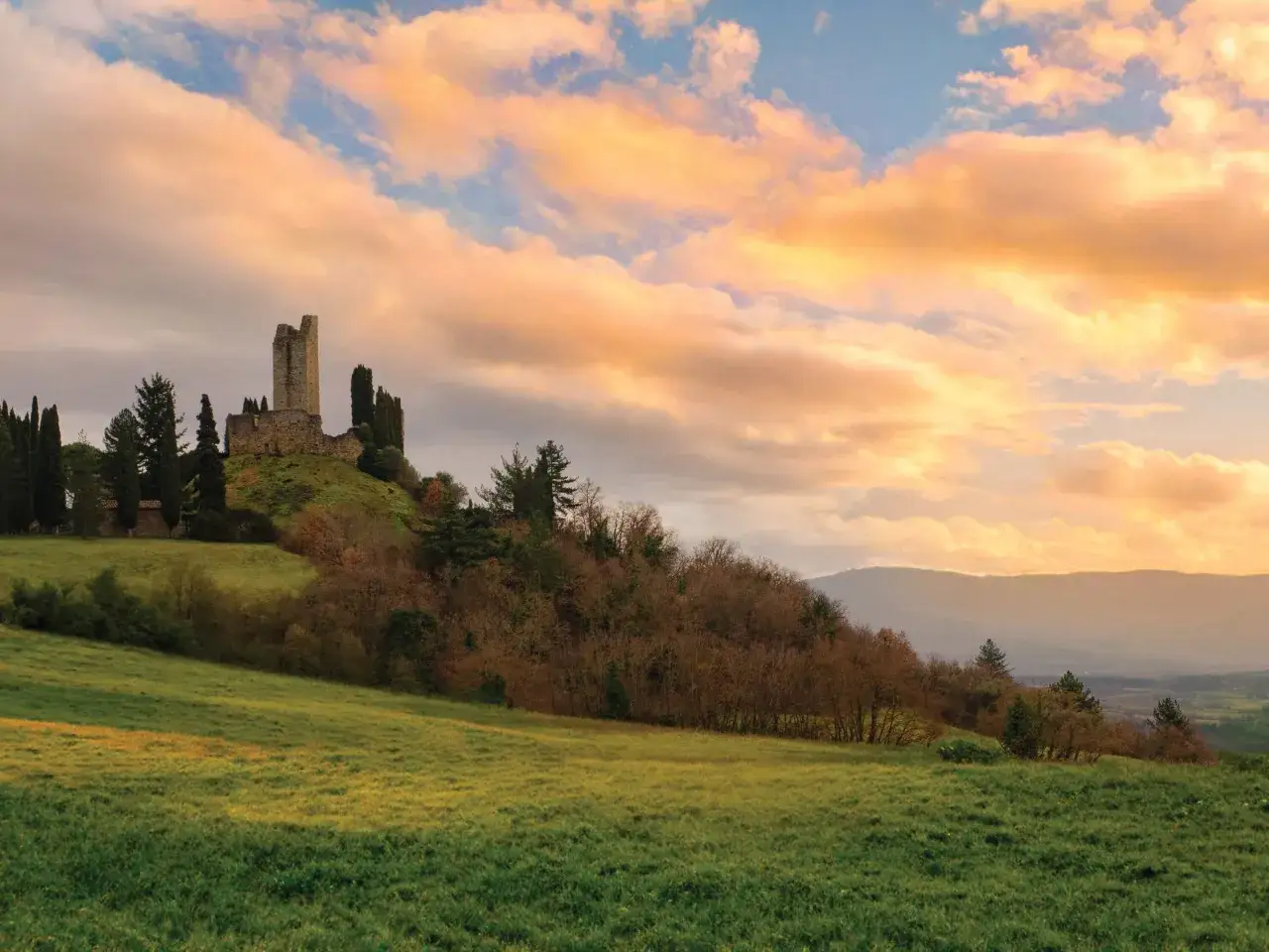 Rovine di un castello su una collina nel Casentino, con un cielo al tramonto dai colori caldi. Un luogo suggestivo da scoprire.