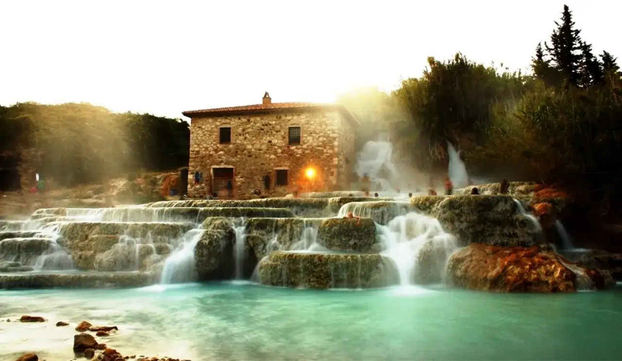 Cascate del Mulino, un luogo magico da vedere a Saturnia, con un antico casale in pietra e acque termali turchesi.