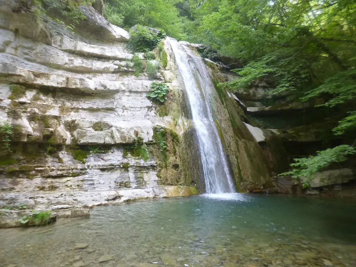 Le cascate dell'Acquacheta scendono maestose tra rocce stratificate e vegetazione lussureggiante, creando un'oasi di pace.