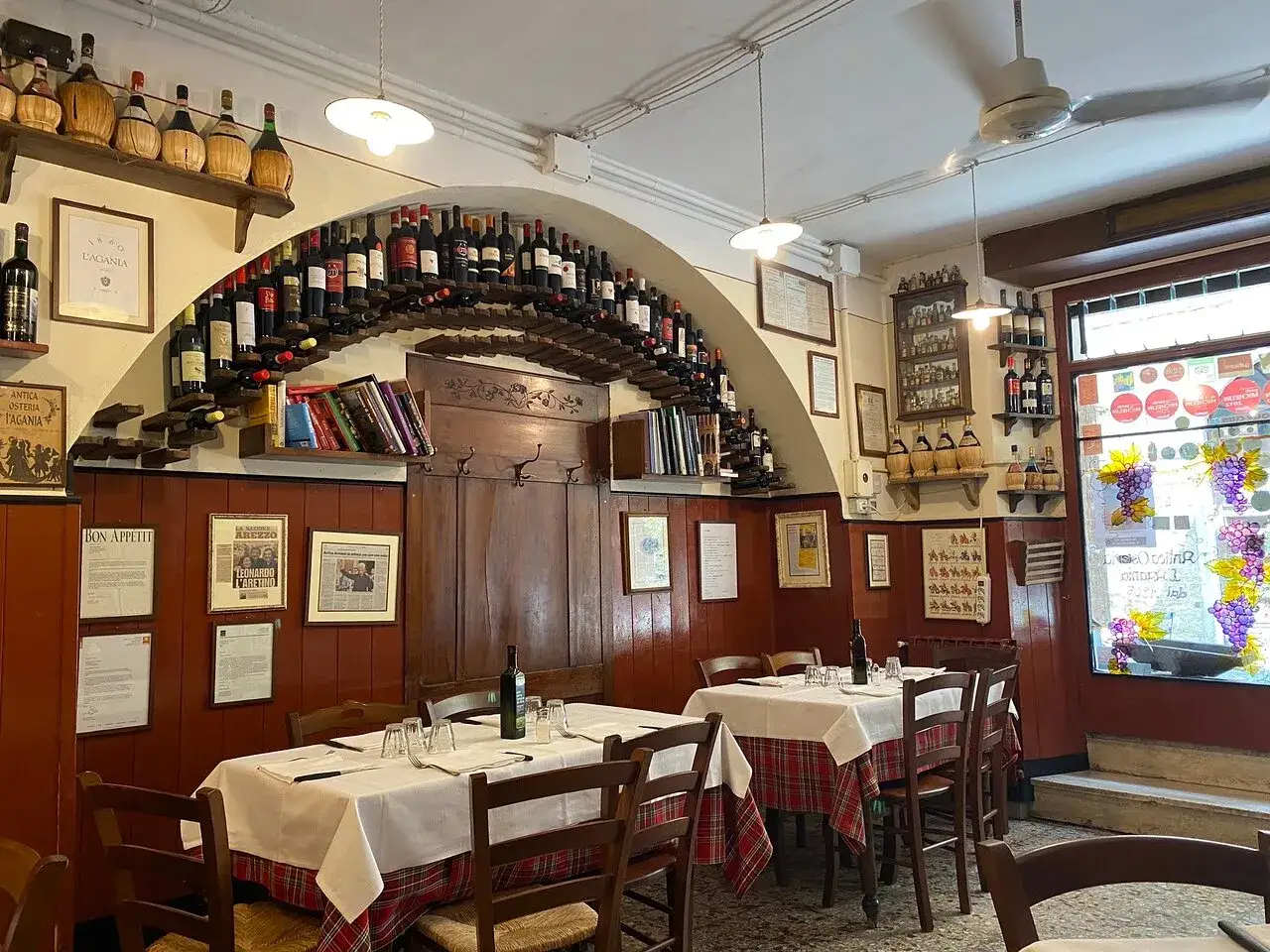 Atmosfera accogliente in una delle osterie Arezzo e dintorni. Tavoli apparecchiati, bottiglie di vino e un'aria di tradizione.