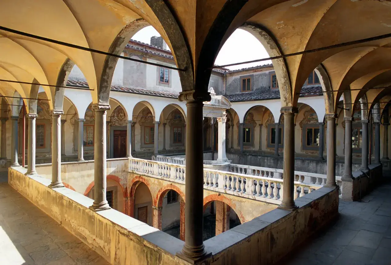 Cortile della Certosa di Calci con archi e colonne, un luogo di pace e storia.
