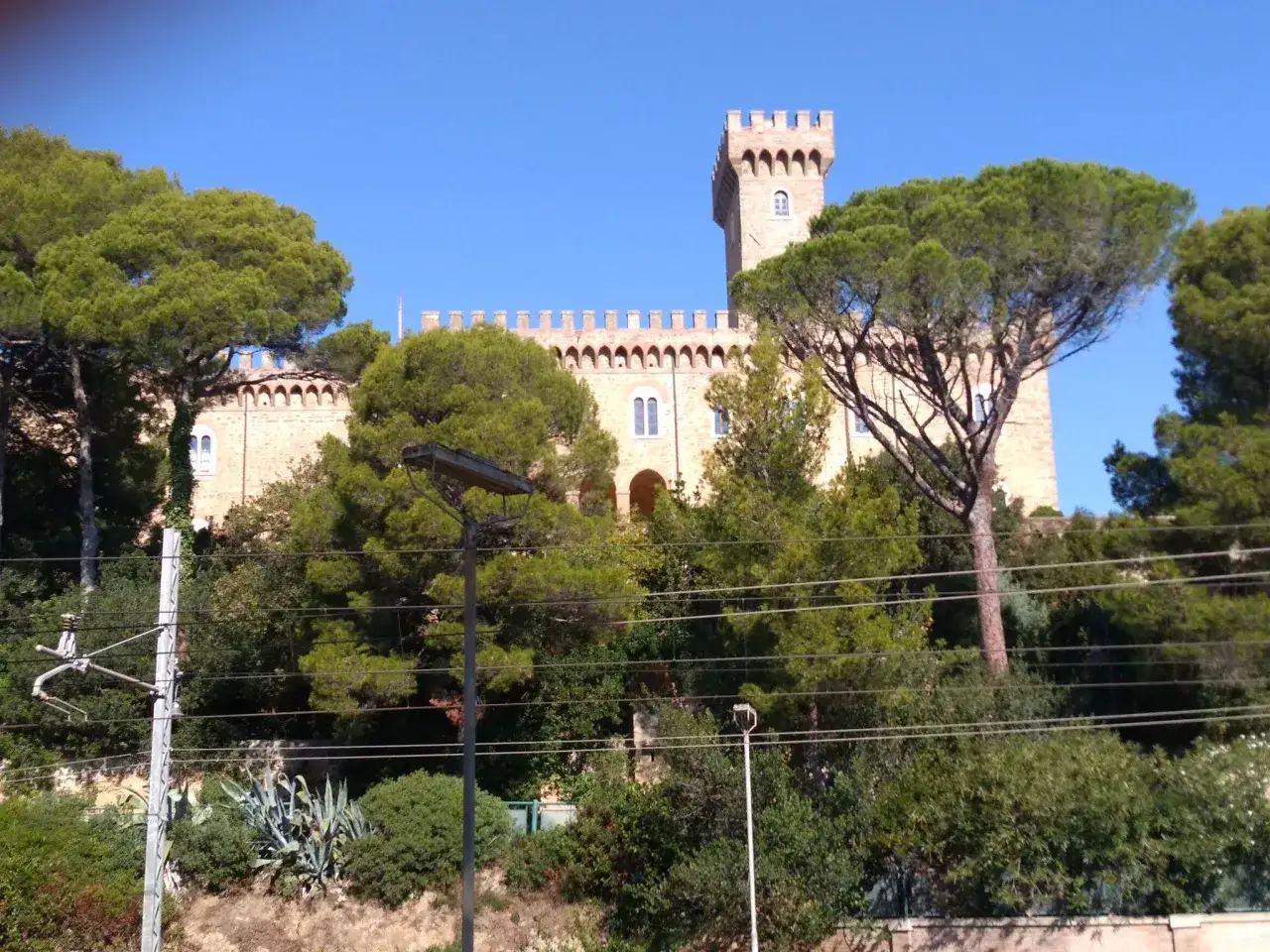 Il castello Pasquini si erge tra alberi verdi e un cielo azzurro.