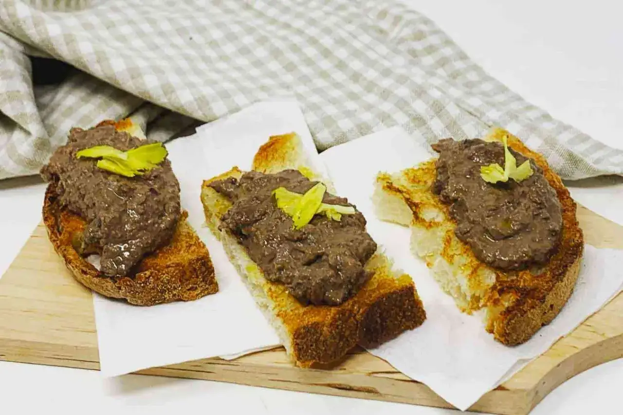 Deliziosi crostini rossi toscani, con pat&eacute; scuro e guarnizione verde, su pane tostato croccante.