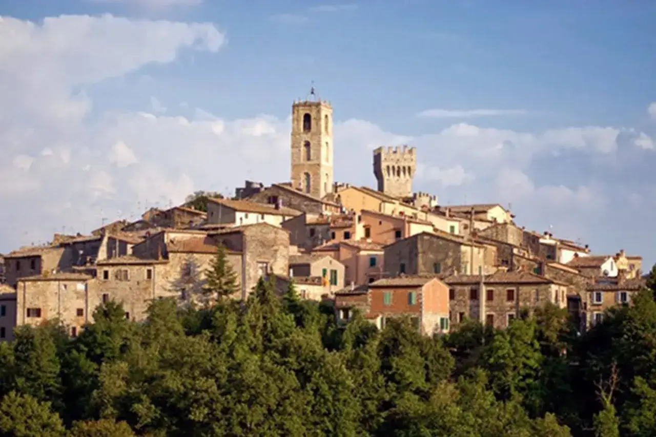 Borgo medievale di San Casciano, con torri e case in pietra, immerso nel verde della campagna toscana.