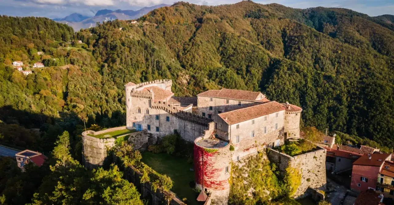 Antico borgo fortificato tra i verdi colli, uno dei magnifici castelli della Lunigiana, con torri e mura che raccontano storie millenarie.