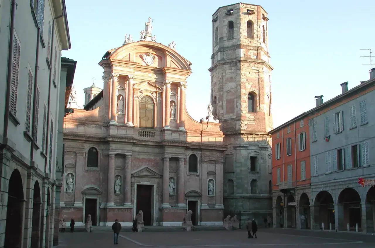 Piazza con chiesa barocca e torre medievale a Montagnano, Arezzo. Edifici colorati e portici completano la scena.
