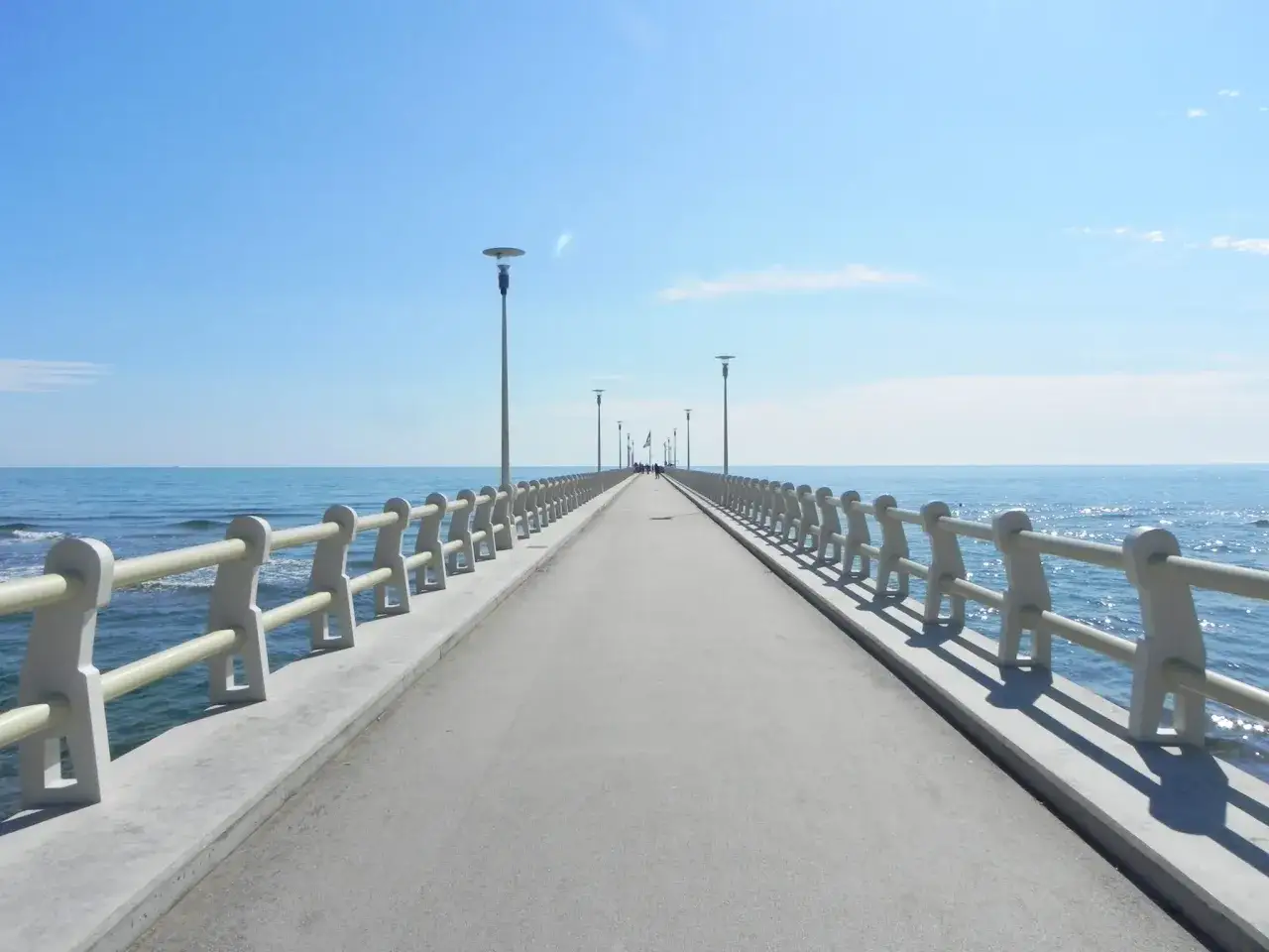 Il pontile di Forte dei Marmi si estende verso il mare azzurro sotto un cielo limpido, invitando a una passeggiata.