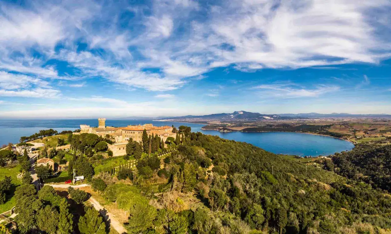 Castello medievale domina la collina nel Val di Cornia, con il mare blu e un paesaggio verdeggiante.