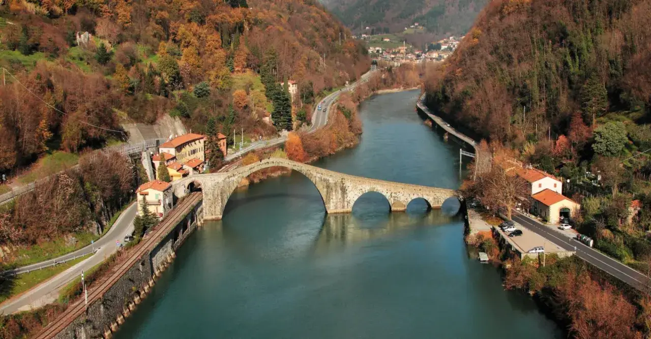 Il Ponte del Diavolo, con le sue arcate in pietra, attraversa un fiume circondato da colline autunnali.