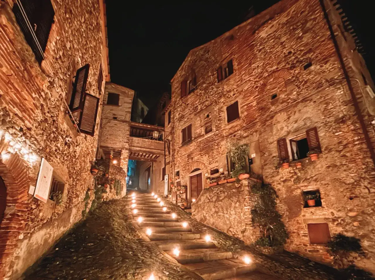 Antica scalinata illuminata da candele in un borgo medievale della provincia di Arezzo.