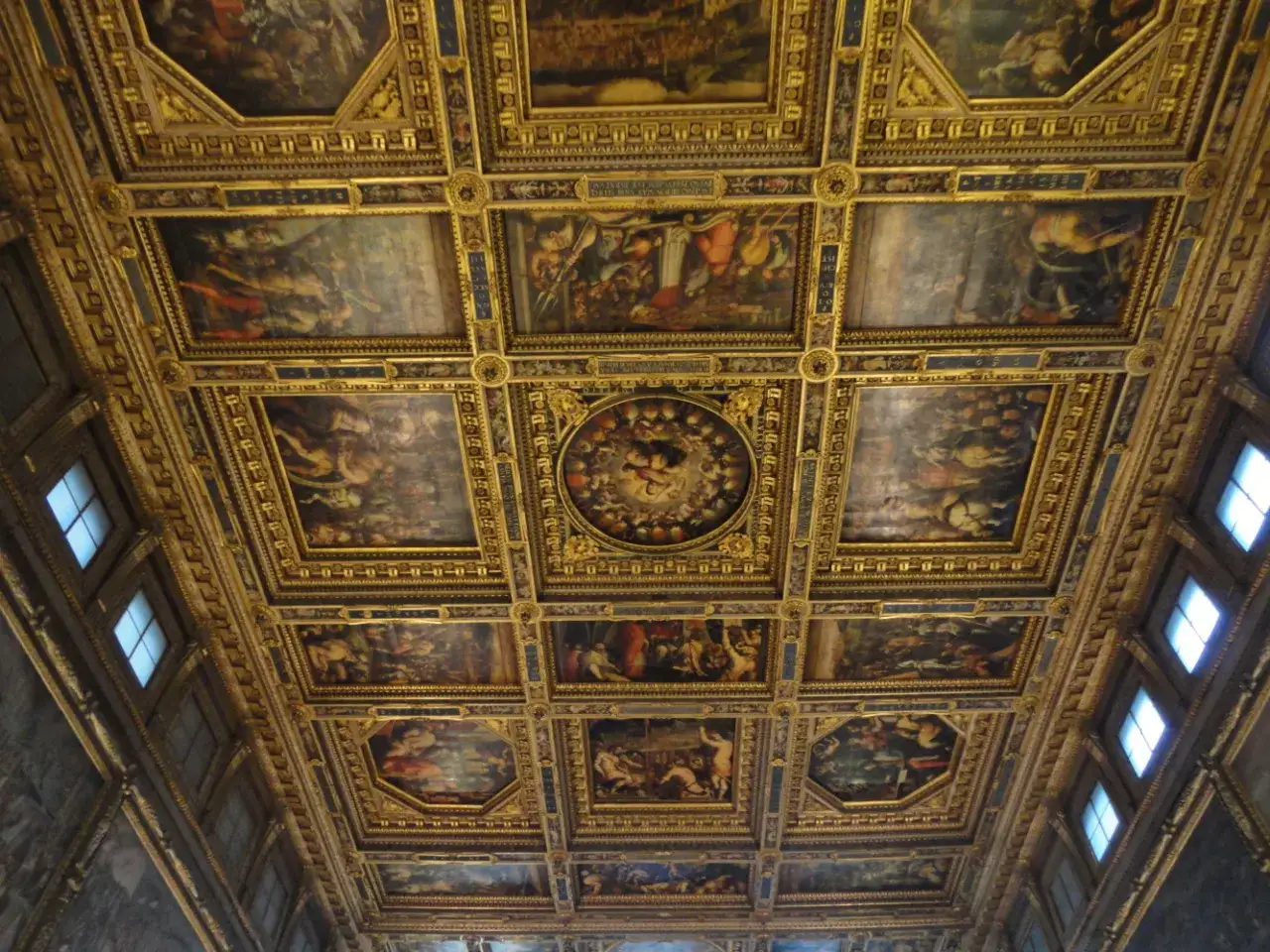 Soffitto a cassettoni dorato e affrescato del Palazzo Vecchio, con scene mitologiche e decorazioni elaborate.