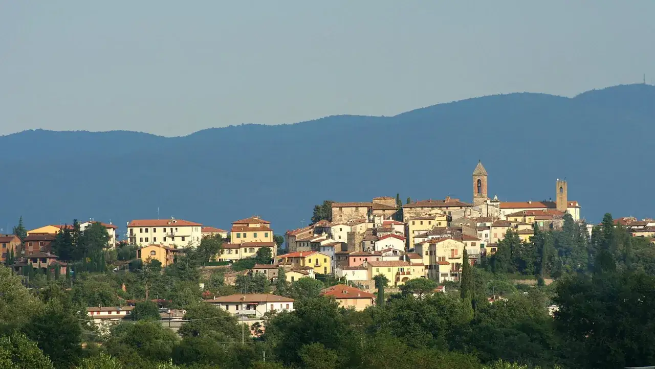 Borgo collinare con case dai tetti rossi e torri, incastonato tra colline verdi. Un paesaggio tipico dei Setteponti Arezzo.