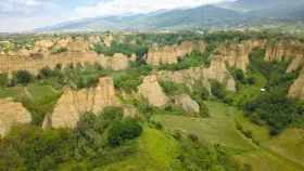 Le suggestive balze del Valdarno, scolpite dal tempo, si ergono tra verdi colline e un borgo in lontananza.