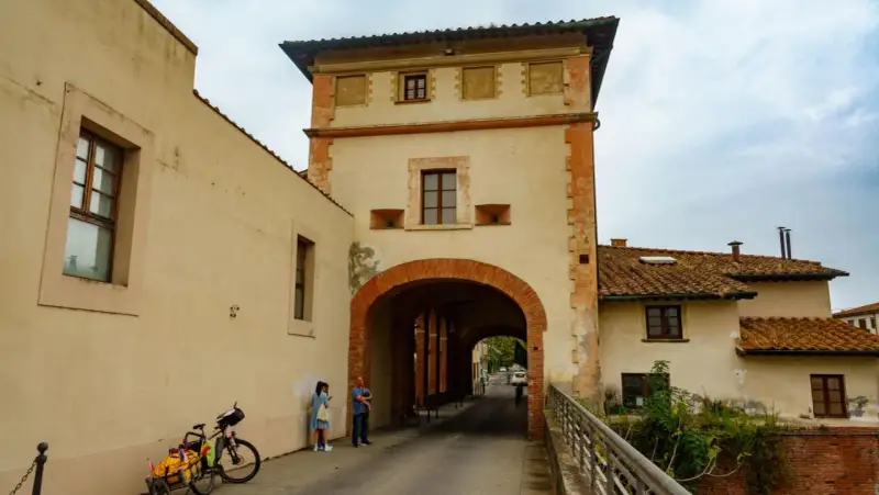 Un arco imponente a Santa Maria a Monte, con una coppia che osserva la strada. Una bici carica attende.