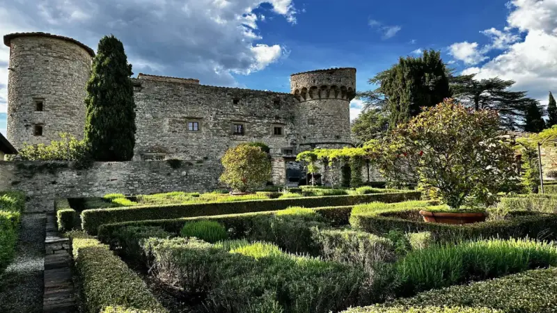 Giardini curati e torri antiche del castello di Meleto, un luogo ideale per visite indimenticabili.