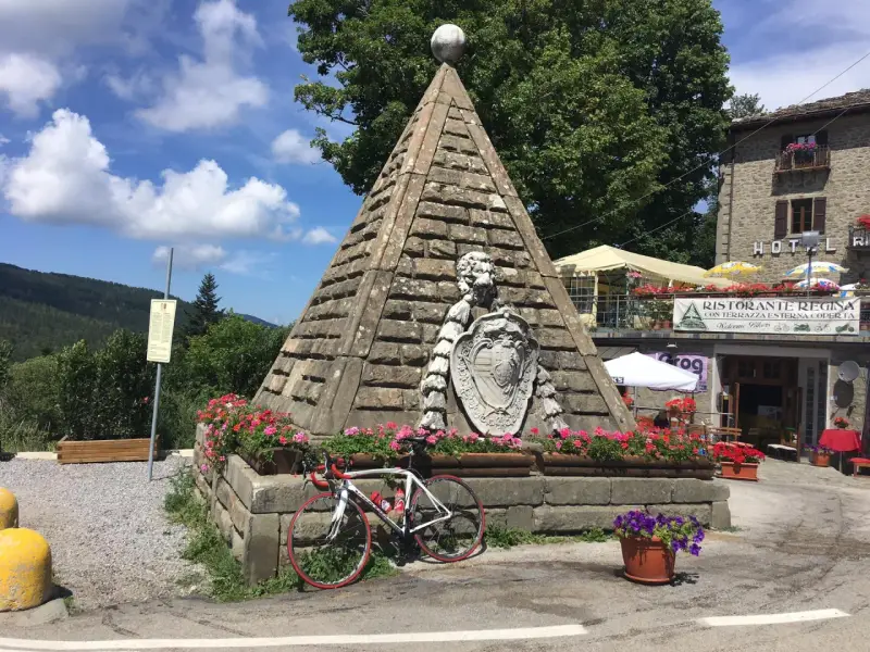 Le piramidi di Abetone, con una bici da corsa appoggiata, circondate da fiori e un ristorante.