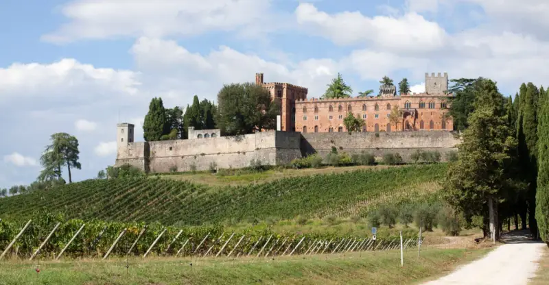 Il castello di Brolio domina le colline toscane, circondato da vigneti rigogliosi e cipressi secolari.