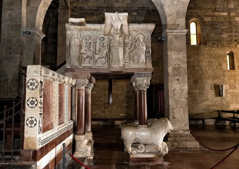 Interno del duomo di Barga con un leone in marmo e un pulpito scolpito.